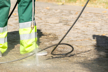 selective focus, a public cleaning worker cleaning the street with high pressurized water