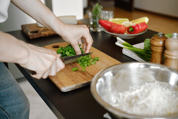 Female hands chopping cilantro on cutting board