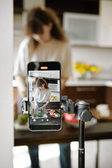 Smartphone recording a focused woman preparing food in a modern kitchen