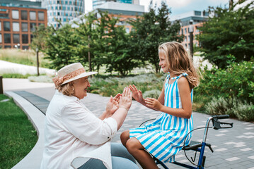 Grandma having fun with granddaugter in the city. Girl sitting on walker, spending time with senior...