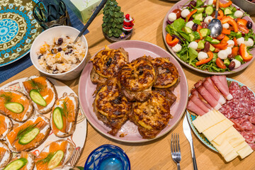A close-up top view of a festive Christmas dinner spread on a wooden table. Homemade dishes