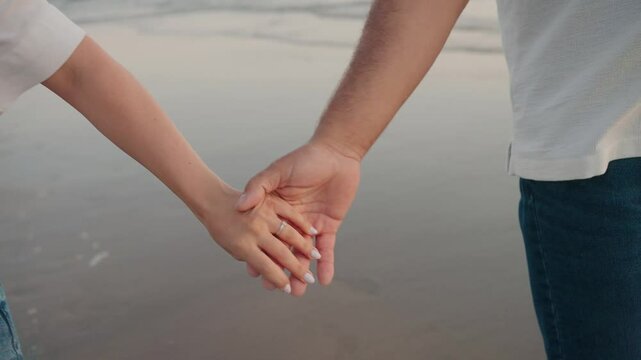 Close up of couple holding hands at the beach, symbolizing love and connection