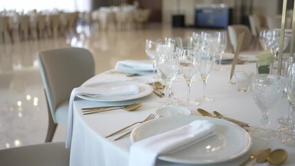 Luxurious table setup with crystal glassware, gold cutlery, and white plates in an elegant venue