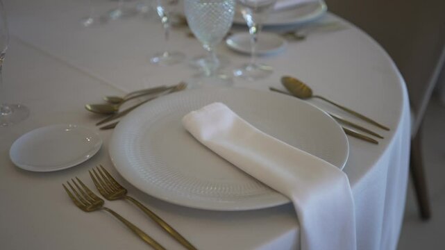 Formal table setting with white plate, gold cutlery, and folded napkin