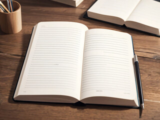 木製のテーブルの上に置かれている開かれたノートと鉛筆