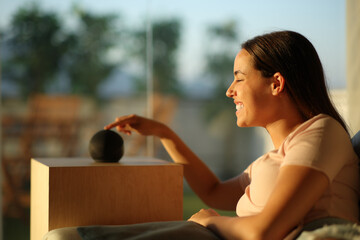 Happy woman using smart speaker at sunset