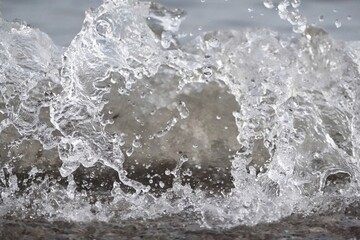 Obraz premium White foam and sea water drop splashes slow motion with sand and blue water