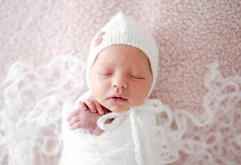 Sleeping Newborn Baby Wrapped In Swaddle Is A Studio Photo Of A Little Girl
