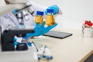 A modern laboratory scene showcasing scientists, both male , in lab coats, analyzing samples using microscopes and computers.