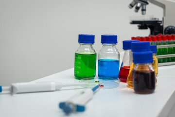 A modern laboratory scene showcasing scientists, both male , in lab coats, analyzing samples using microscopes and computers.
