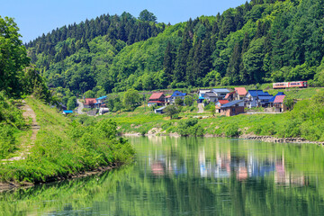 Fototapeta premium 千曲川に寄り添って暮らす家々の側を抜ける飯山線の観光列車