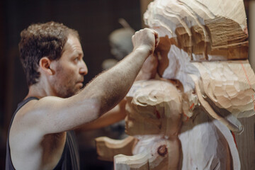 Artisan wood carver using chisel on wooden sculpture