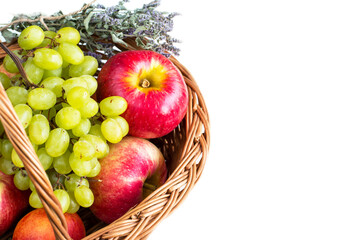 White background with Ripe red Apples, dry marjoram herbs and green grapes in the basket