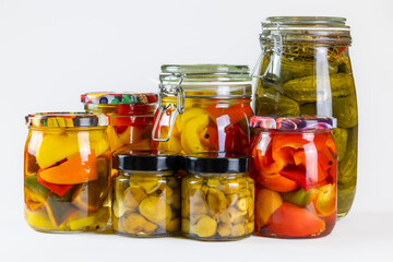 A variety of jars with pickled vegetables, such as peppers, mushrooms, and cucumbers. The jars come in different shapes and sizes, and the contents are colorful vegetables immersed in a marinade.