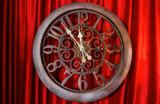 metal Christmas clock at five to twelve red background curtains, beautiful flounces. Concept: Christmas New Year New Year Resolutions. dial clock hands which show time five minutes twelve. Clode up.