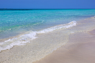 Empty sea beach with white sand, view to azure waves and blue sky. Caribbean coast clean transparent water, background for holidays on a paradise nature