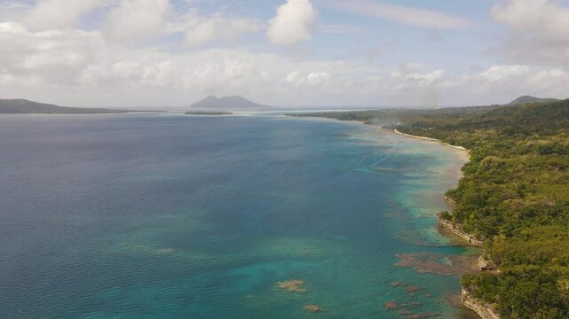 Drone aerial pan over Top Rock in Vanuatu showing a tropical mountain and teal vast ocean