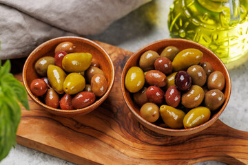 An assortment of various olives presented in a bowl, showcasing different colors, textures, and...