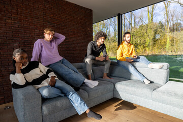 A diverse group of friends is calmly sitting on a modern couch in a bright and stylish living room with panoramic views
