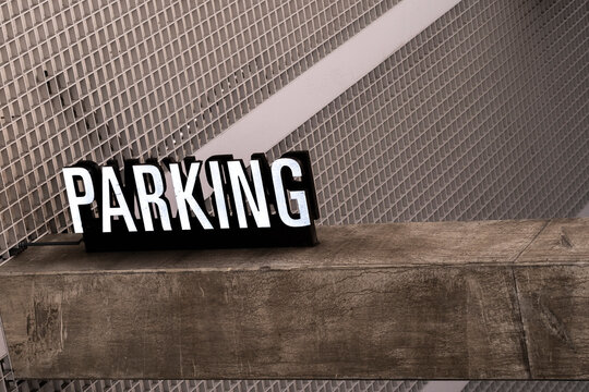 This image shows a 'Parking' sign against a metal mesh background with a textured wooden beam beneath it, blending urban industrial design with rustic elements.