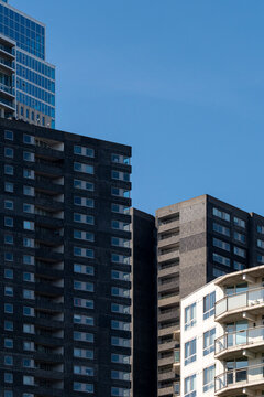 A close-up view of a dark, modern high-rise apartment complex with multiple windows and structural details, highlighting urban living and architectural design trends in Rotterdam