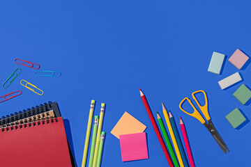 Top view of colorful school supplies on blue background