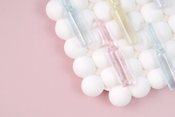 Top view of skincare ampoules on a background of white spheres