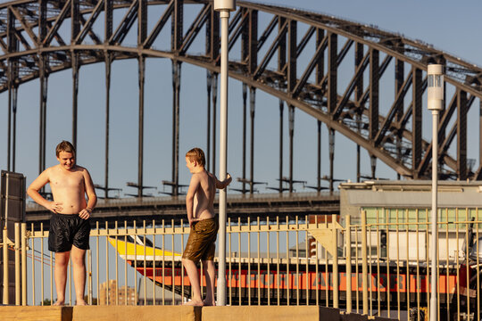 Wet kids jumping standing on ledge at Marrinawi Cove with Sydney Harbour Bridge in background