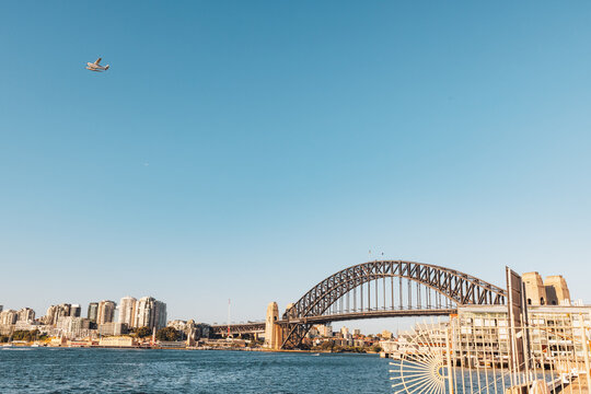 Seaplane flying over the Sydney Harbour Bridge on bright day with blue sky