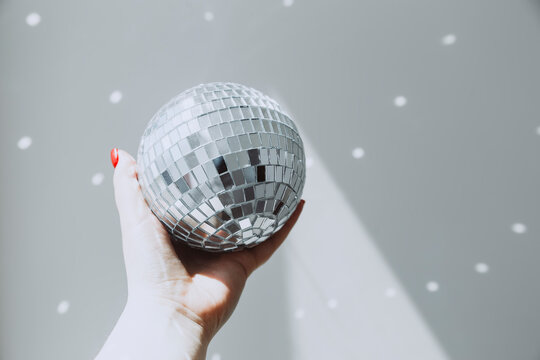 Hand holding a small disco ball reflecting light