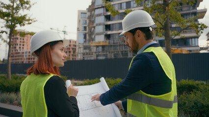Two contractors civil engineers checking information in blueprint discuss teamwork pointing city...