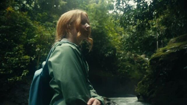 Young woman enjoying a tropical rainforest waterfall in the jungle 