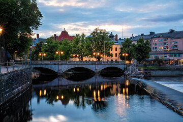 Orebro town cityscape with stone bridge over Svartan river and historic buildings on background innthe evening. Uncrowded destinations and historic architecture concept. Sweden