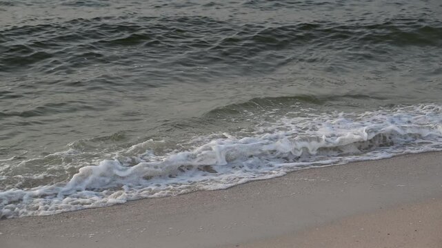 Sea waves splashing on the shore, creating foam on a beach