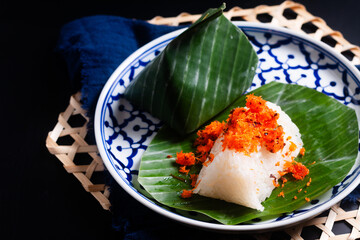 Food concept thai snack or dessert Kao Niew Na Koong  coconut Gelatinous or sticky  rice with shrimp topping on banana leave  on black background