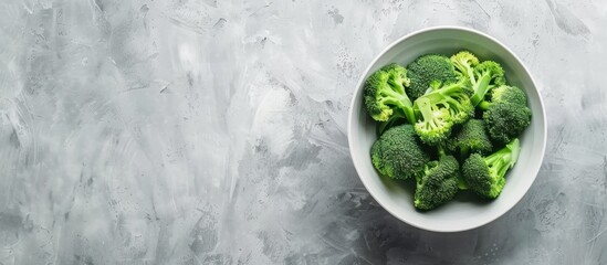 Obraz premium Bowl of fresh broccoli on a gray table Area for text. with copy space image. Place for adding text or design