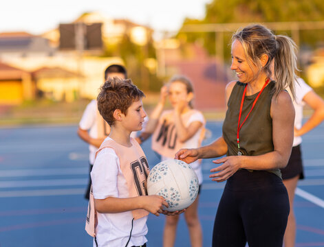 lady with whistle on lanyard coaching children's netball team
