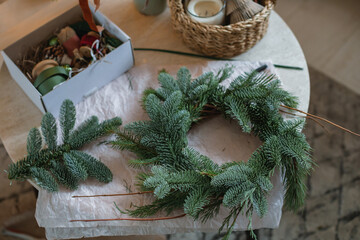 Overhead view of a Christmas fir wreath being made and decorations on a table