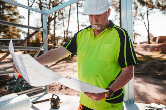 A contractor holding and looking at the construction blueprint.