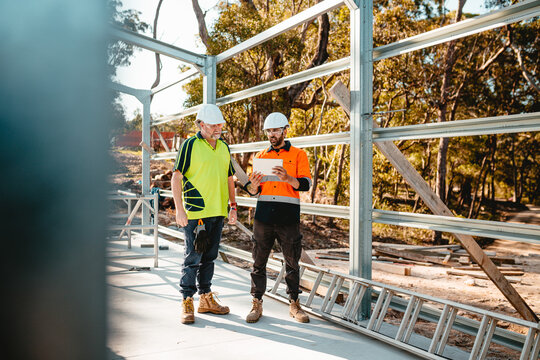 Two construction site managers looking at the digital blueprints