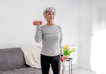 Elderly Sweet Woman Exercises With Dumbbells, Embracing Active Lifestyle And Home Workouts