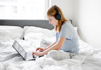 Girl Sits In Bed With Laptop In Bright Room In The Morning