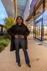 Obraz premium A trendy, fashionable woman is standing confidently outside a modern and stylish retail space, exuding confidence