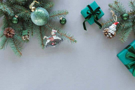 Overhead view of two wrapped Christmas gifts, fir branches, Christmas baubles, ornaments and decorations on a grey background