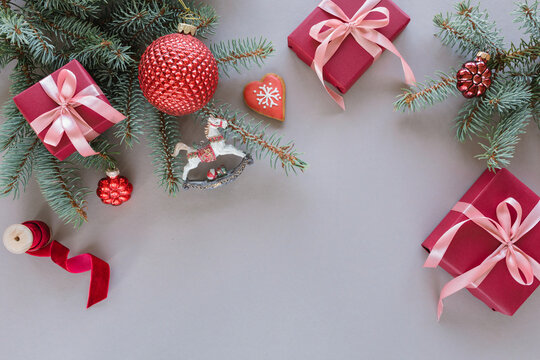 Overhead view of two wrapped Christmas gifts, fir branches, Christmas baubles, ornaments and decorations on a grey background