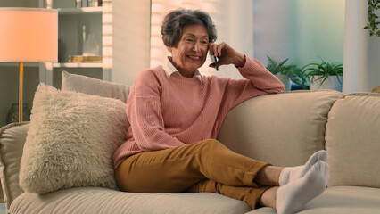 Relaxed happy laughing old woman on cozy sofa talking on smartphone laugh discuss funny news carefree smiling senior grandmother at comfy couch at home elderly lady female retired speak mobile phone