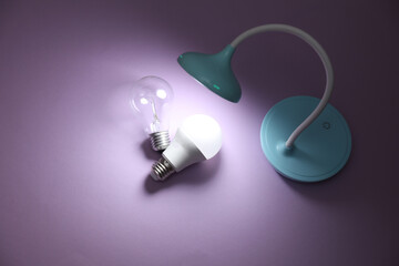 Table LED lamp and light bulbs on purple background. Energy efficiency, saving