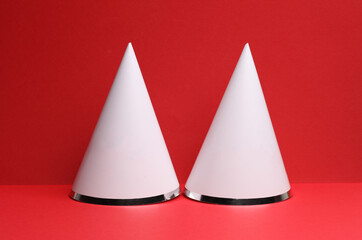 Fototapeta premium White birthday cones caps mockup on a red background