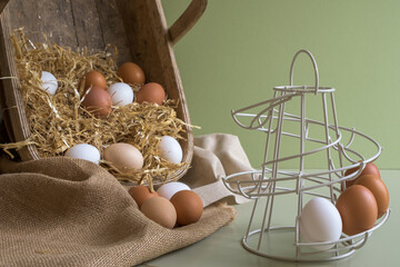 Farm chicken eggs stacked into a wire tower. Basket filled with straw and free range hens eggs.
