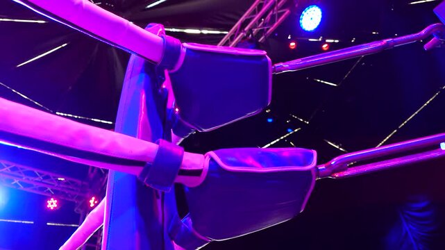 Close-up of corner of boxing ring as colorful lights flash in stadium